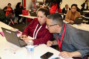 Student and a restaurant worker sitting in front of a laptop
