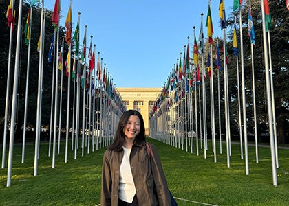 A UCLA Law student standing amidst flags outside of The Hague