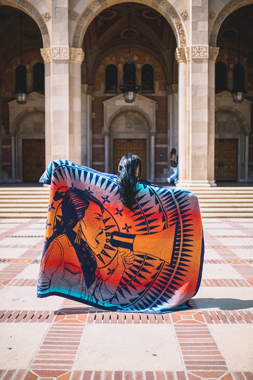 Individual holding a Native Amrican blanket in front of Royce Hall