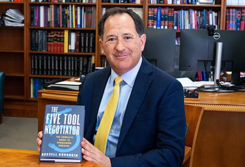 Russell Korobkin holding a copy of his book, The Five-Tool Negotiator: The Complete Guide to Bargaining Success